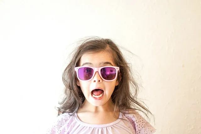 Girl wearing reflective pink sunglasses with an excited facial expression